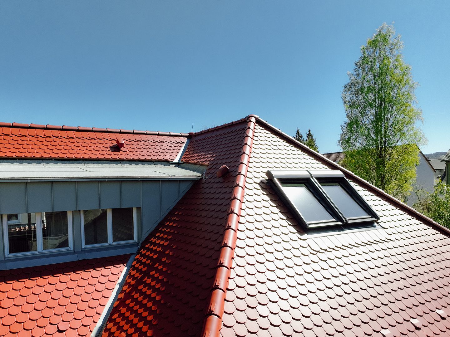 Professionelle Dachsanierung mit roten Dachziegeln und moderner Dachfensterlösung