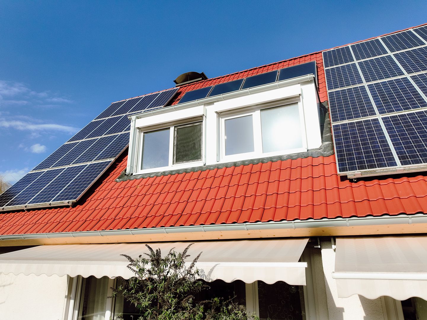 Photovoltaik auf modernisiertem Hausdach mit roten Dachziegeln und Dachgaube