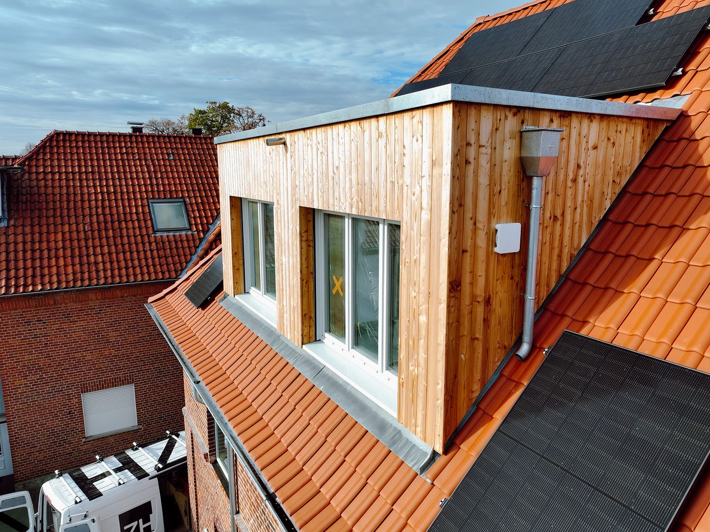 Moderne Dachgaube mit Holzfassade und Photovoltaikanlage auf Steildach