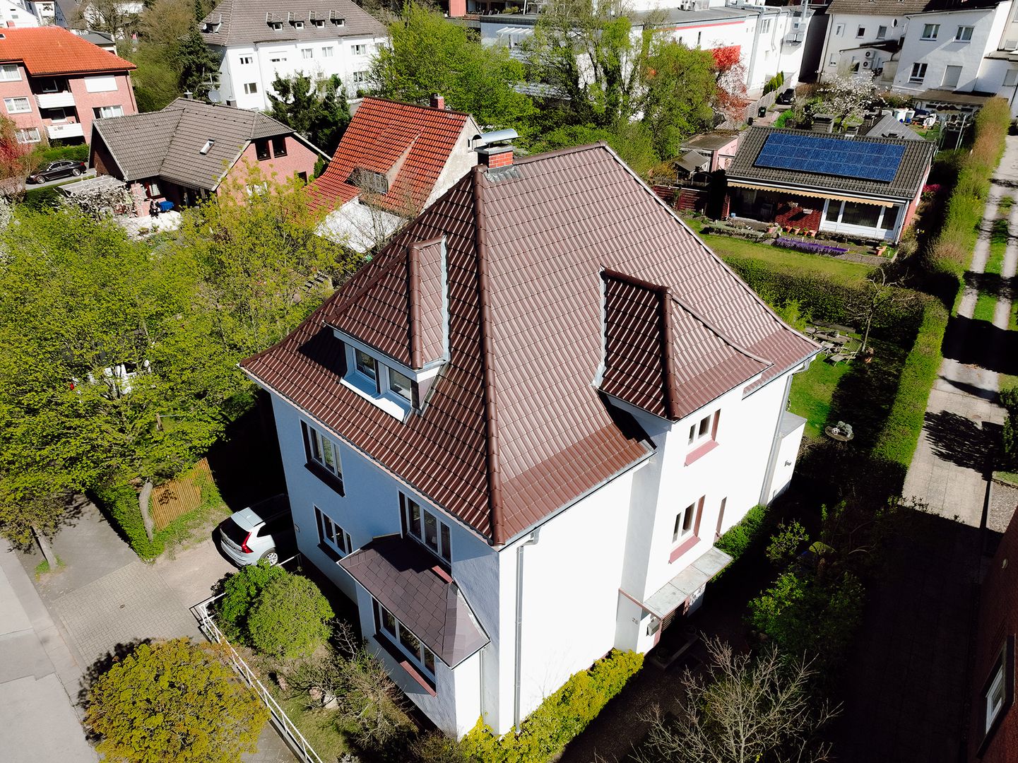 Luftaufnahme eines Einfamilienhauses mit neu eingedecktem Walmdach und Dachgaube