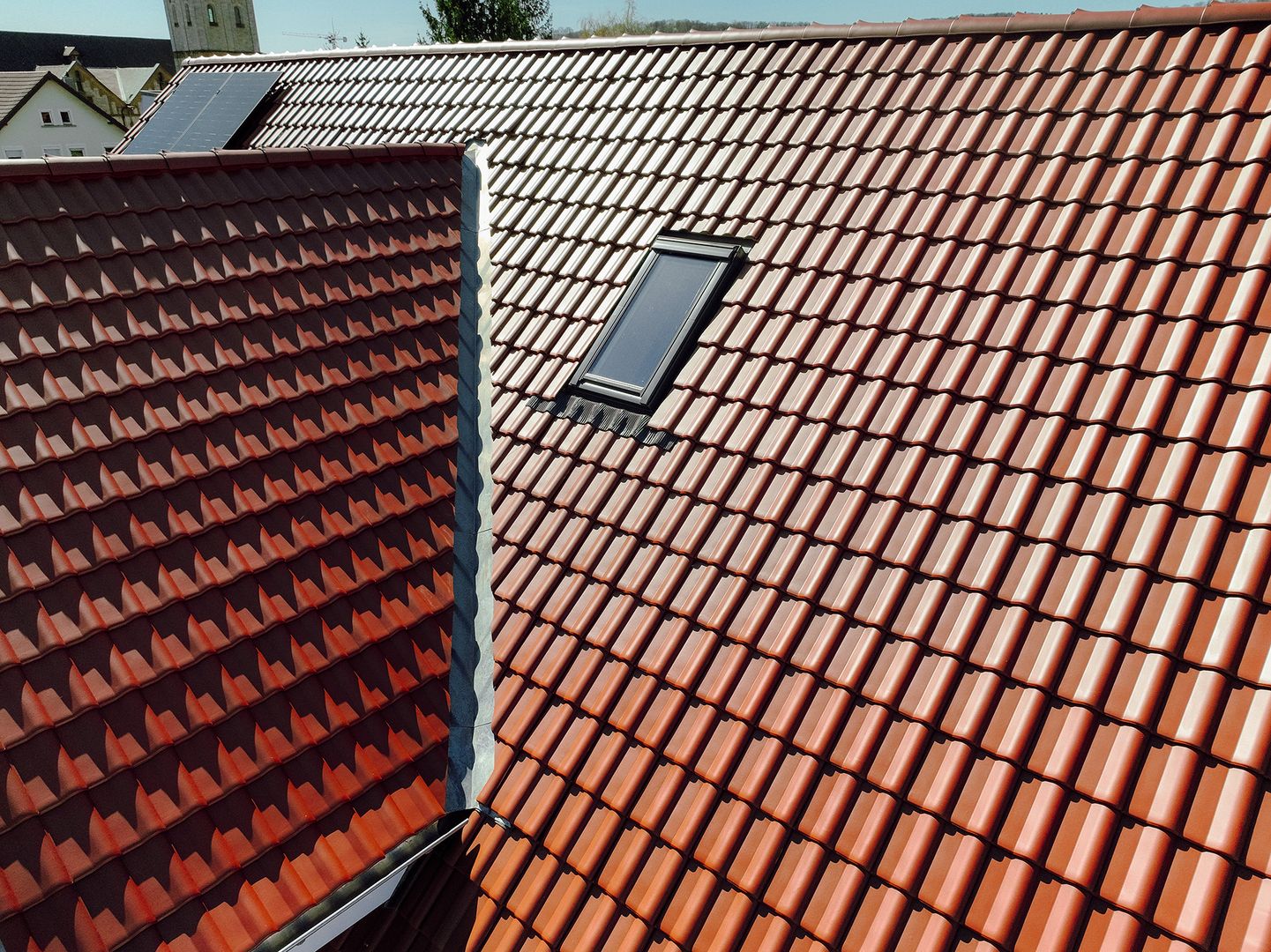 Detailaufnahme eines roten Hausdachs mit Dachfenster
